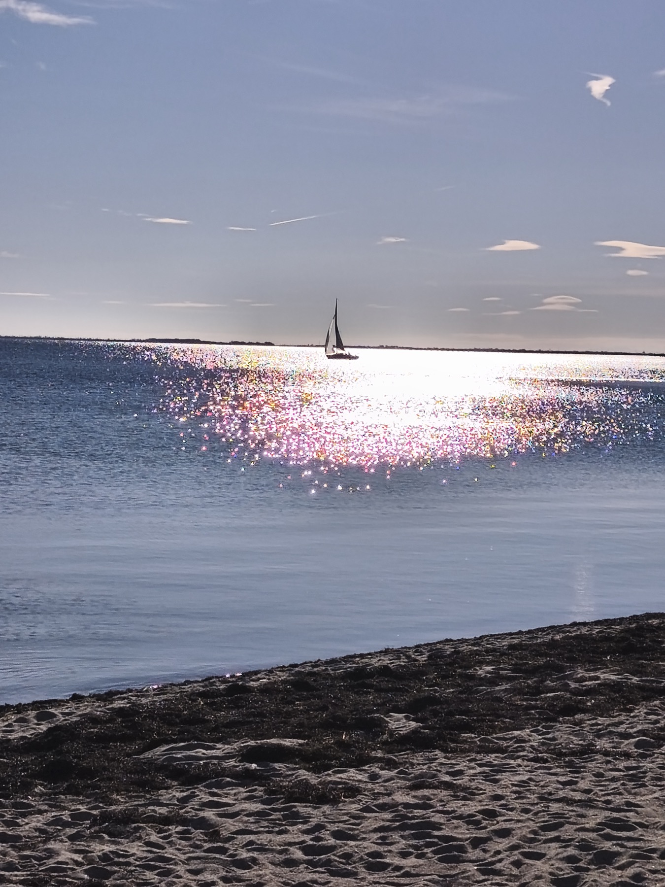 Voilier sur le bassin de Thau avec reflets du soleil