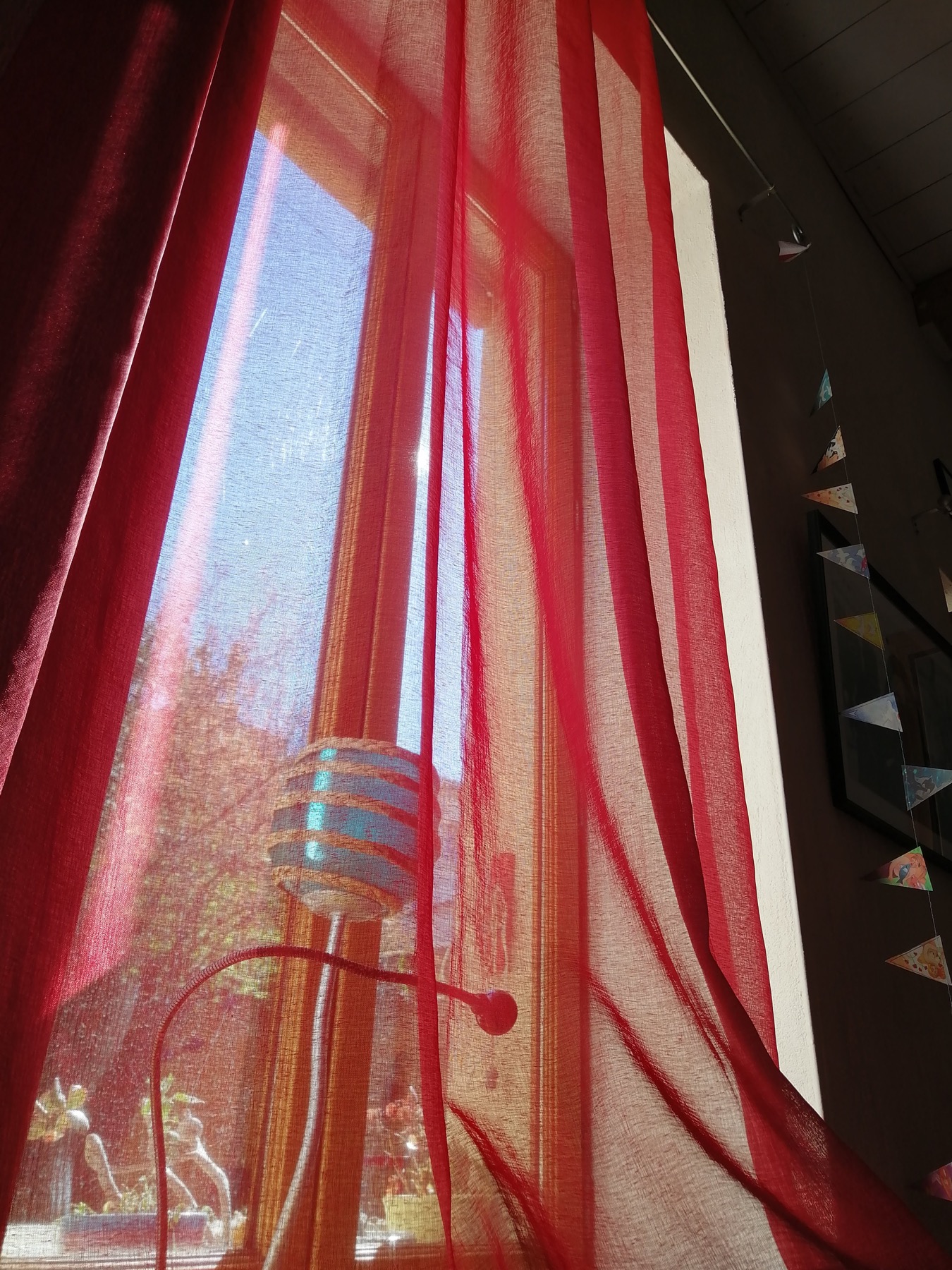 Rideaux rouges traversés par la lumière dans le gîte