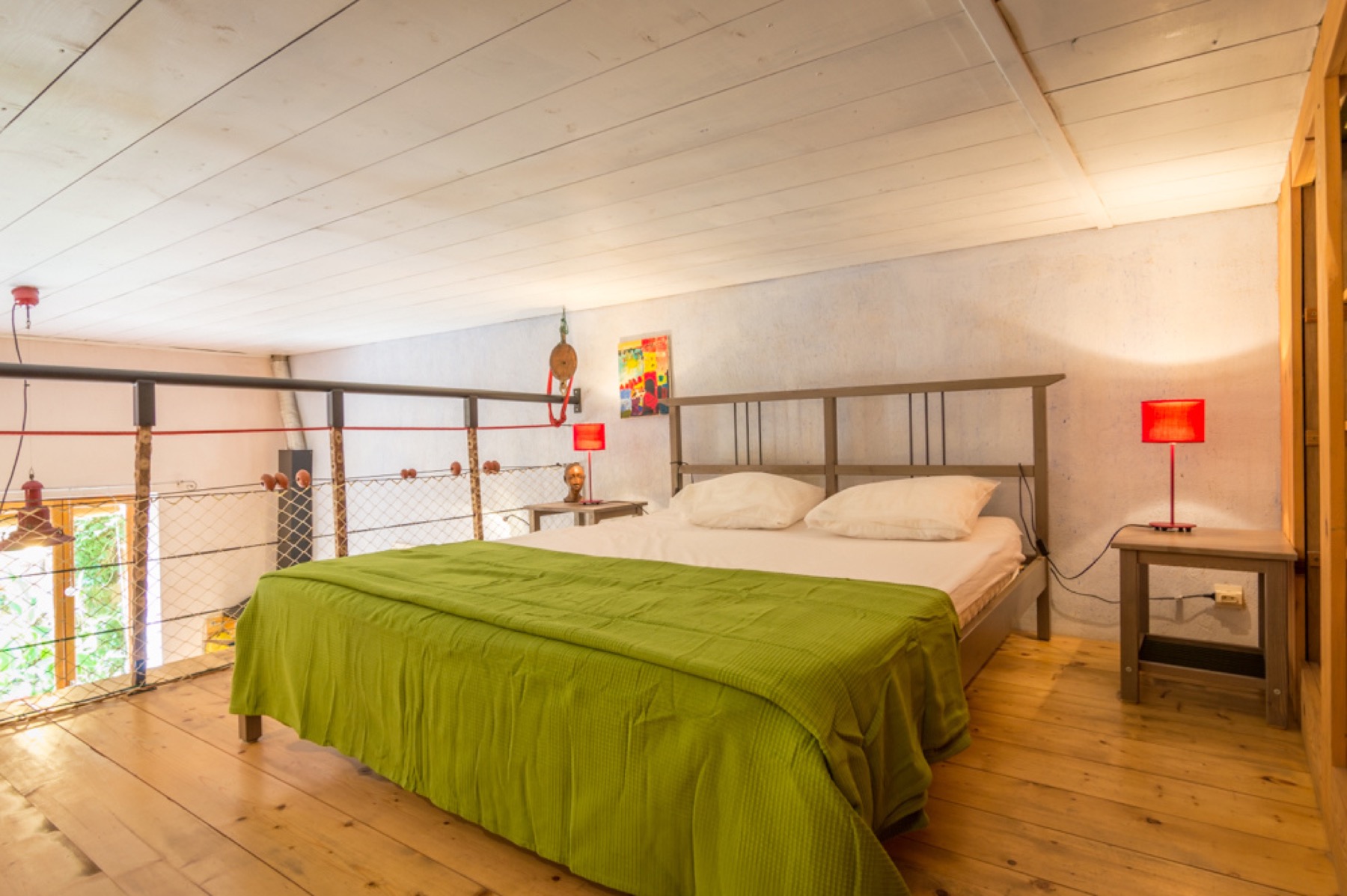 Lit double en mezzanine avec couverture verte et lumière douce