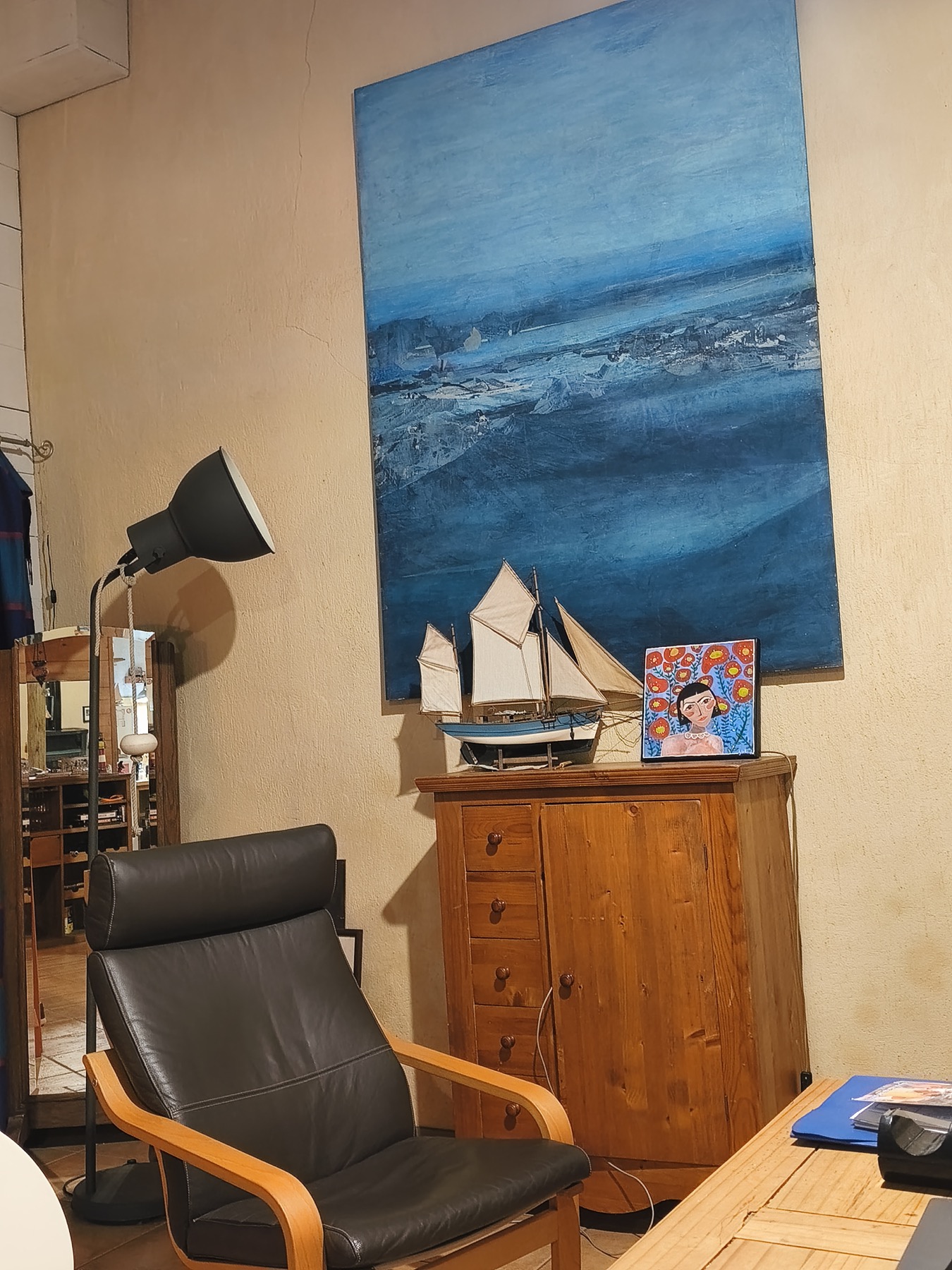 Détail du salon avec fauteuil, tableau marin et mobilier bois